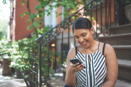latina immigrant woman looking at her phone to do her finances
